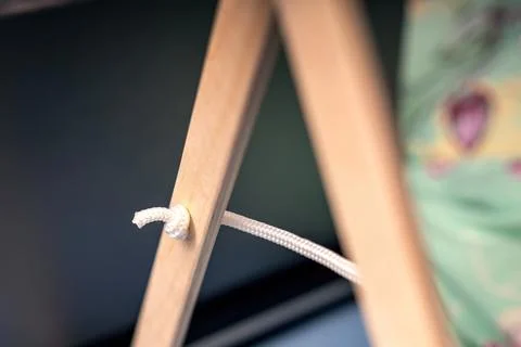 Thick white rope threaded through a hole in a wooden board, tied in a knot .. Foto stock