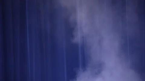 Thick white smoke drifting against dark curtain with blue light Stock Footage 346354951