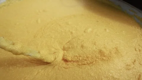Thick yellow batter being stirred with a wooden spoon in a large bowl Stock Footage 339286467