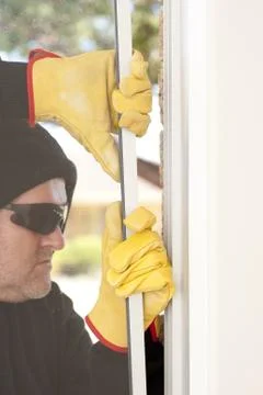 Thief breaking through window of home Foto stock