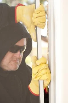 Thief breaking through window of house Stock Photos