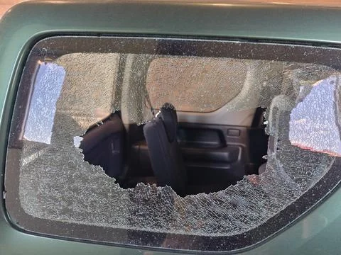 Thief broken car window. Criminal incident and vandalism on the city streets. Stock Photos