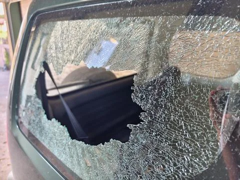 Thief broken car window. Criminal incident and vandalism on the city streets. Stock Photos