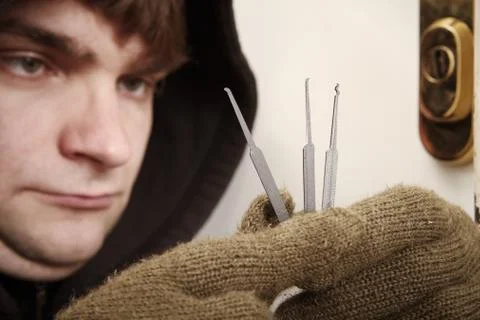 Thief experimenting with plastic lockpick tools to try break in property Stock Photos