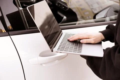 Thief hacking car system with laptop near vehicle, closeup Stock Photos