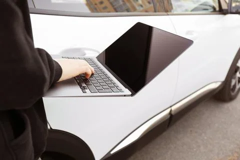 Thief hacking car system with laptop near vehicle, closeup Stock Photos