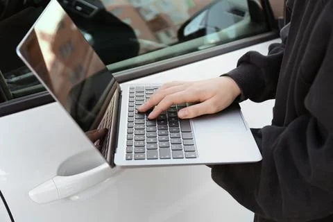 Thief hacking car system with laptop near vehicle, closeup Stock Photos