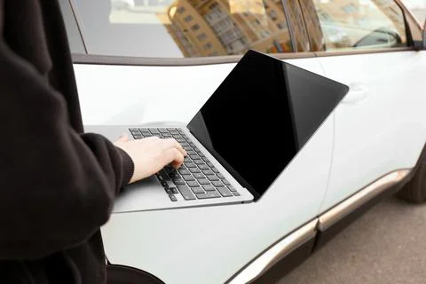 Thief hacking car system with laptop near vehicle, closeup Stock Photos