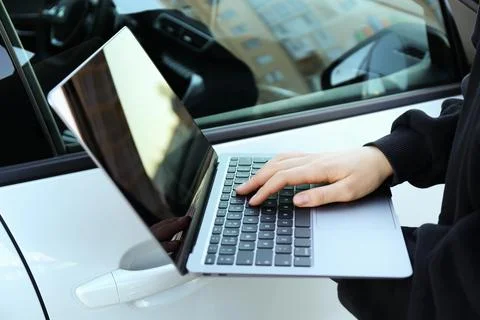 Thief hacking car system with laptop near vehicle, closeup Stock Photos