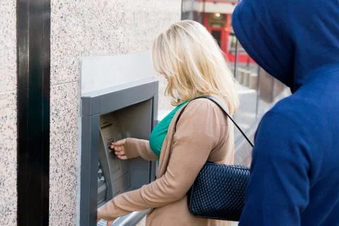 Thief looking over womans shoulder at cash machine Stock Photos