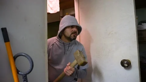 Thief man with a sledgehammer in his hands with a terrible look enters the do Stock-Footage 117146582