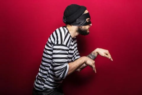 A thief with mask slinking on red background Stock Photos