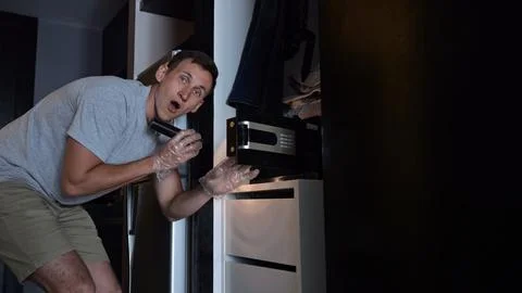 Thief opens hotel safe box lighting up face with excitement Stock Photos