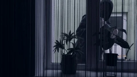 A thief or bandit in a mask breaks open a window with a crowbar and breaks into Stock Footage 273606690
