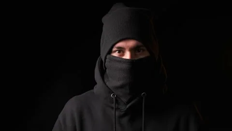 Thief staring at the camera while standing on a dark background. Stock-Footage 198335660