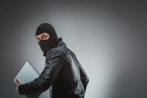 Thief stealing a laptop computer. Isolated on gray background Stock Photos