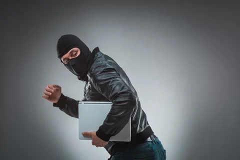Thief stealing a laptop computer. Isolated on gray background Stock Photos
