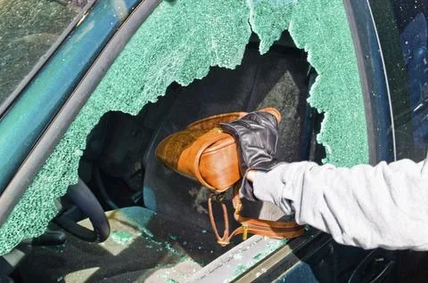 A thief steals a handbag from a car through a broken side window. Austria Stock Photos