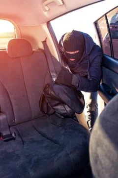 Thief taking handbag from car back seat Stock Photos