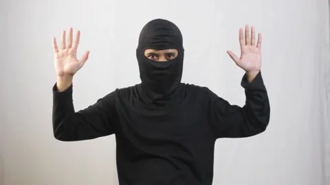 Thief wearing a black mask raised both hands to surrender Stock Footage 319367151