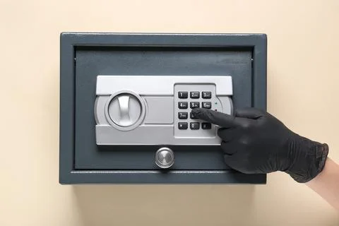 Thief's hand breaking into safe on beige background Stock Photos