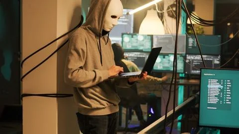 Thieves with anonymous masks hacking computer to steal information Stock Photos