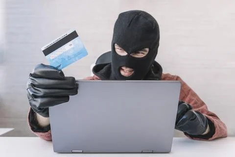 Thieves hold credit cards using a laptop computer for password hacking activi Stock Photos