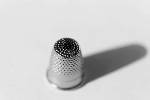 A thimble from above on white background in sunlight with long shadow Stock Photos