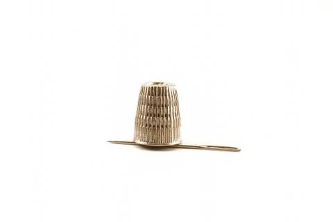 Thimble and needle. On a white background close-up. For sewing. Stock Photos