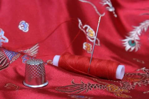Thimble and Thread on Asian Red Silk Stock Photos