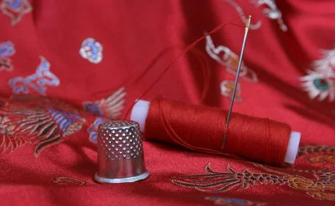 Thimble and Thread on Asian Red Silk Stock Photos