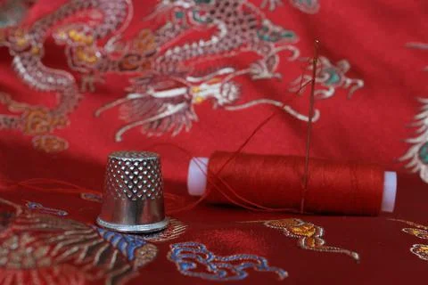 Thimble and Thread on Asian Red Silk Stock Photos