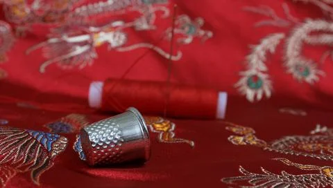 Thimble and Thread on Asian Red Silk Stock Photos