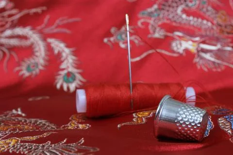 Thimble and Thread on Asian Red Silk Stock Photos