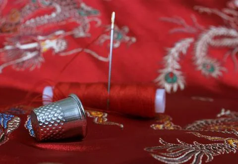 Thimble and Thread on Asian Red Silk Foto stock