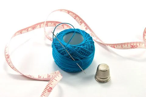 Thimble,needles and blue thread ball for sewing on a background thread 写真素材