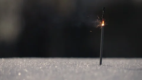 A thin and weak Bengal or Indian light, or sparkler, stick into snow Stock Footage 86429599