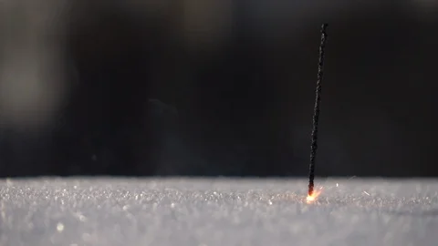 Thin and weak Bengal or Indian light, or sparkler, stick into snow Stock Footage 86429617