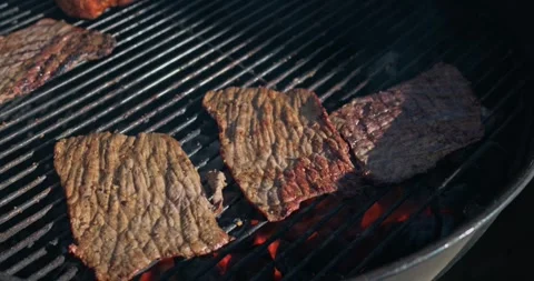 Thin beef slices sear on a charcoal grill during an outdoor barbecue Video stock 330623163