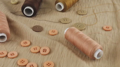 Thin beige cotton jersey, buttons and spools of threads in different shades. Stock-Footage 290813382