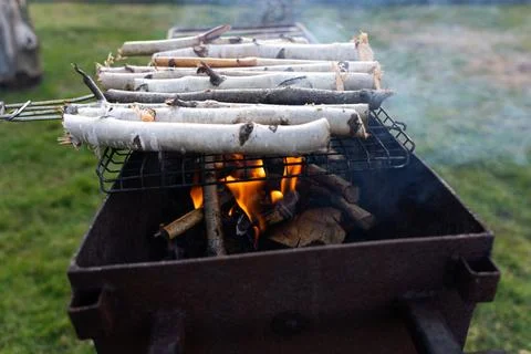 Thin birch twigs are lying on the grill. Thin firewood on the grill Stock Photos