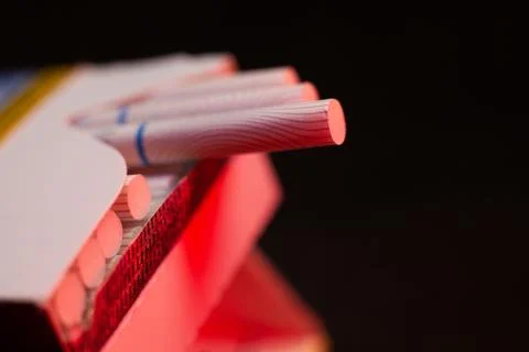 Thin cigarettes with a filter in red light, smoking causes heart attacks Stock Photos