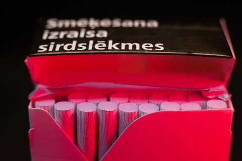 Thin cigarettes with a filter in red light, smoking causes heart attacks Stock Photos