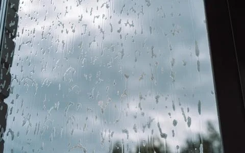 Thin cleaner trails running down a window against cloudy sky Foto stock