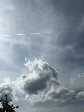 Thin Contrail Crossing Bright Cloudy Sky Stock Photos