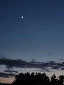 Thin crescent moon in a clear evening sky, astronomy and nocturnal peace Stock Photos