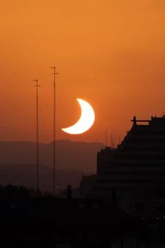Thin crescent sun of partial eclipse near mountain ridge Stock Photos