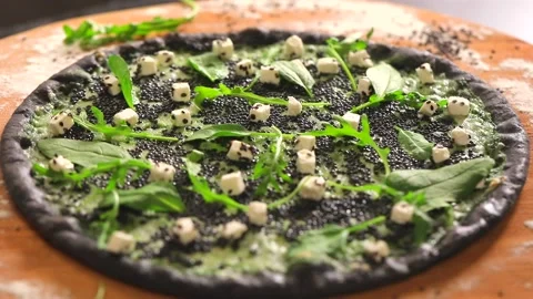 Thin dark pastry pizza with black caviar, cheese, spinach and arugula Stock Footage 130903104