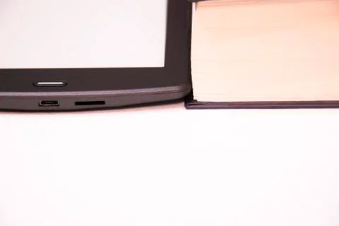 Thin e-book is next to a thick paper book. Stock Photos