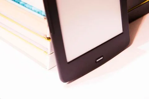 Thin E-book stands next to paper books. New paper technologies. Stock Photos
